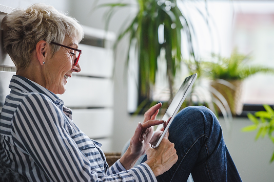 Woman using a tablet at home to browse helpful resources for people living with dermatomyositis