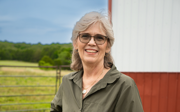 See the VALOR Study Results Glennis, a real patient taking LISRAYA for dermatomyositis, standing outdoors by a barn