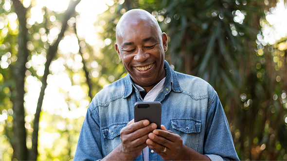 Man smiling while using his smartphone to explore LISRAYA patient support options