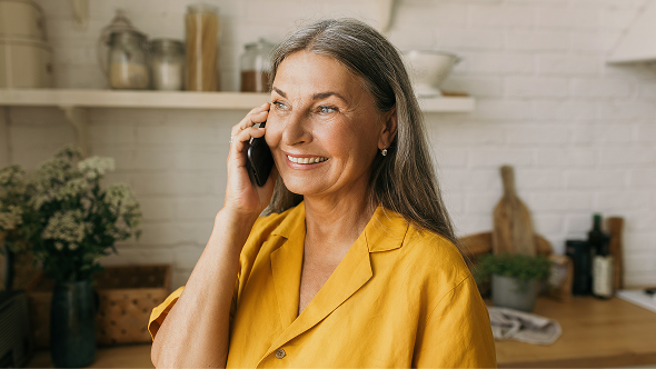 Smiling woman on a phone call discussing cost assistance for LISRAYA